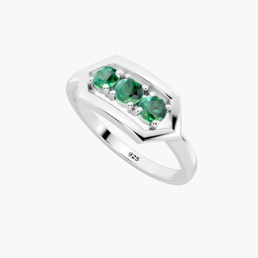 Silver ring with three green emerald stones on a white background